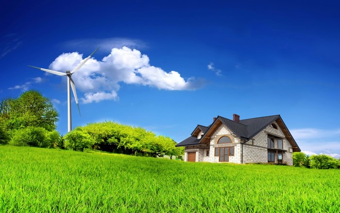 House and wind turbine on a grassy hill under a blue sky