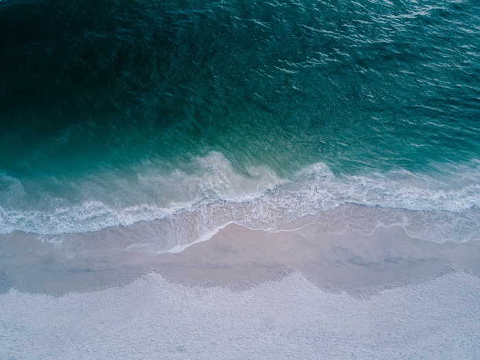 Aerial view of ocean waves crashing on a sandy beach