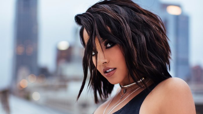 Becky G in black top with city background