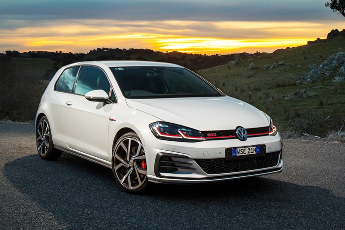 White Volkswagen Golf GTI parked on a road at sunset