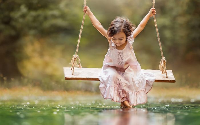 A young girl on a swing over water