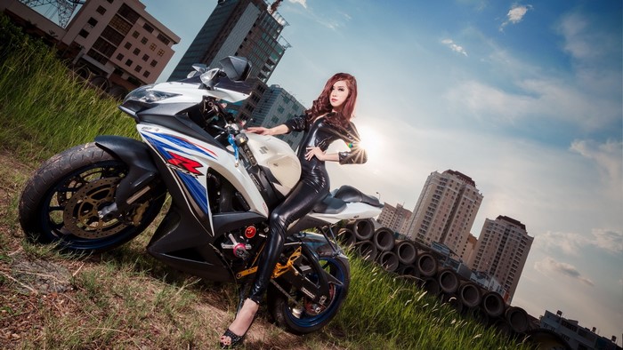 Woman in black outfit on Suzuki motorcycle