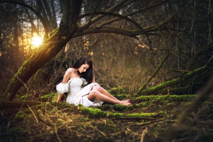 Girl in white dress sitting in a forest