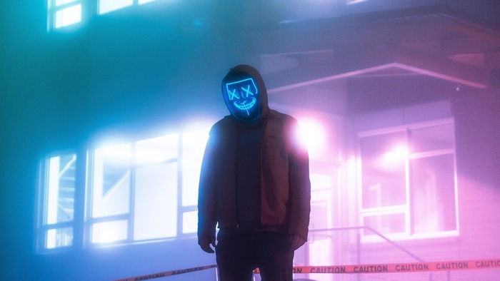 Person wearing a neon mask in front of a building