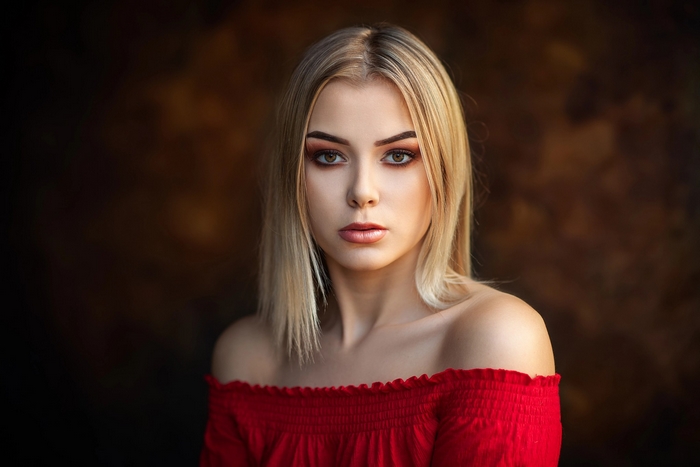Blonde woman with hazel eyes wearing a red off-the-shoulder top
