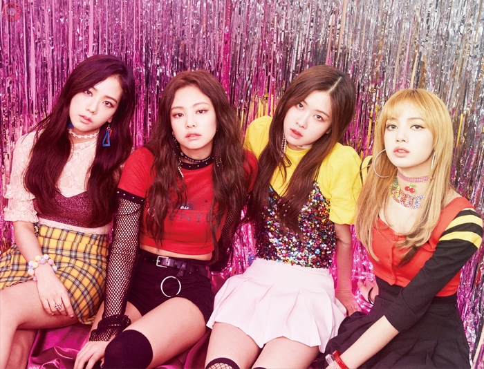 Blackpink members posing in front of a pink backdrop