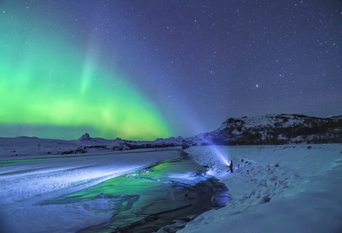 Aurora Borealis over Iceland with a person holding a flashlight