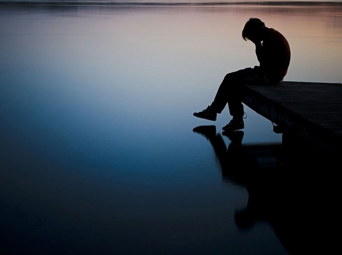 Silhouette of a person sitting on a dock over water