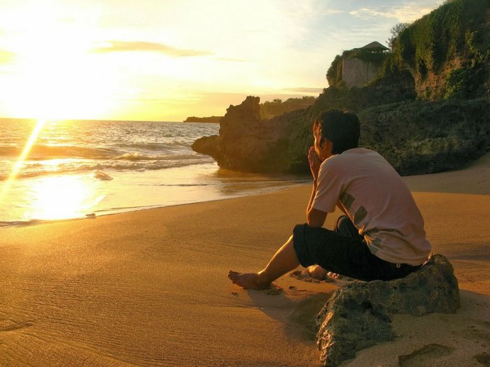 Contemplative Man Sitting Alone on Beach at Sunset