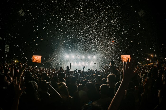 Crowd at a music festival with confetti and stage lights