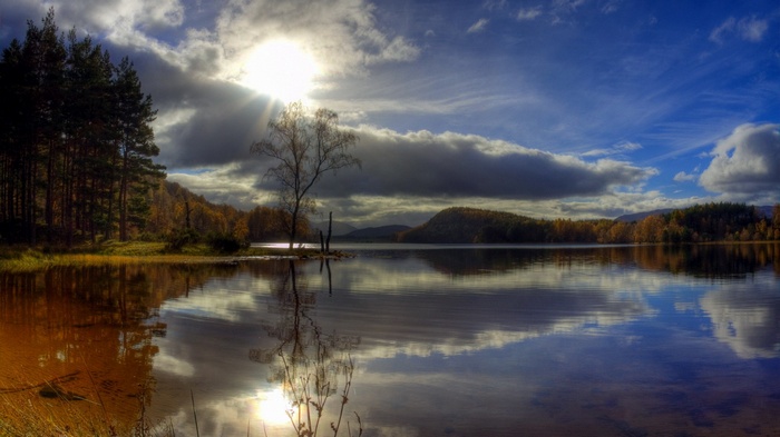 Lake reflection with trees and sunbeams