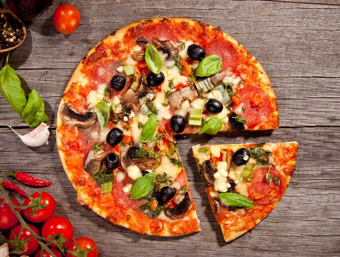 Pizza with salami, mushrooms, olives, and cheese on a wooden table