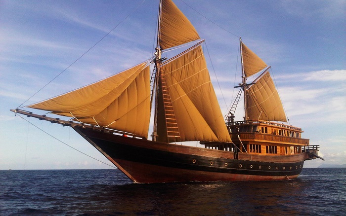Wooden sailing ship with tan sails on the ocean