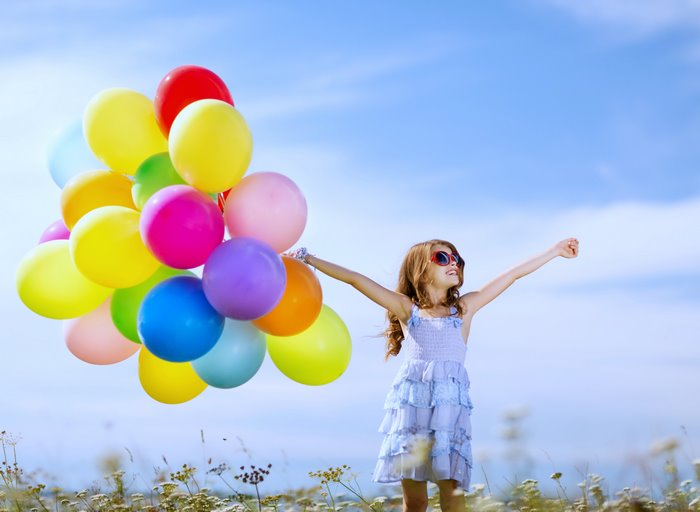 Girl holding colorful balloons in a field