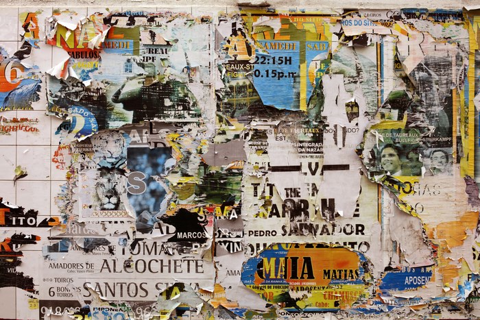 Torn posters on a tiled wall in Portugal