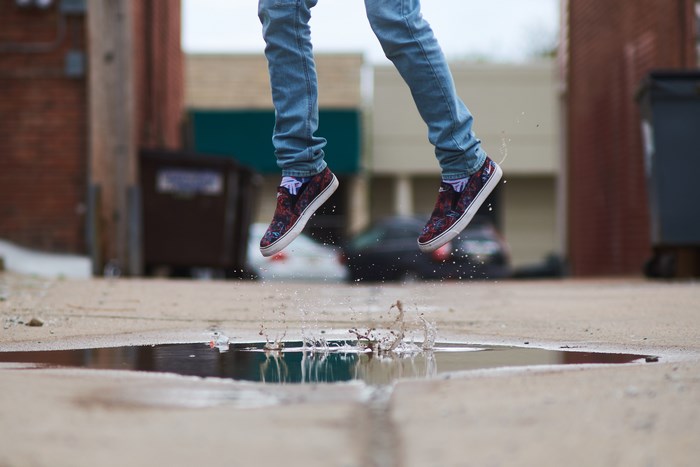 Person jumping in a puddle wearing Vans shoes