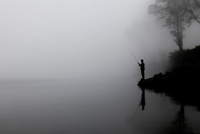 Silhouette of a fisherman in the fog