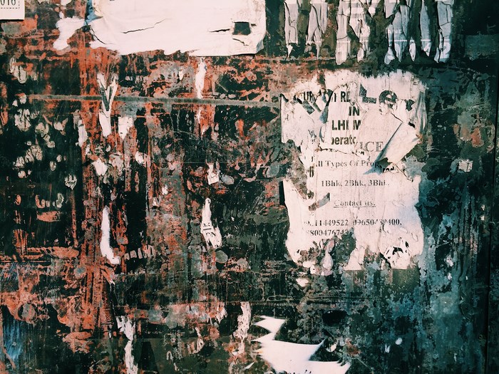 Torn posters on a textured urban wall