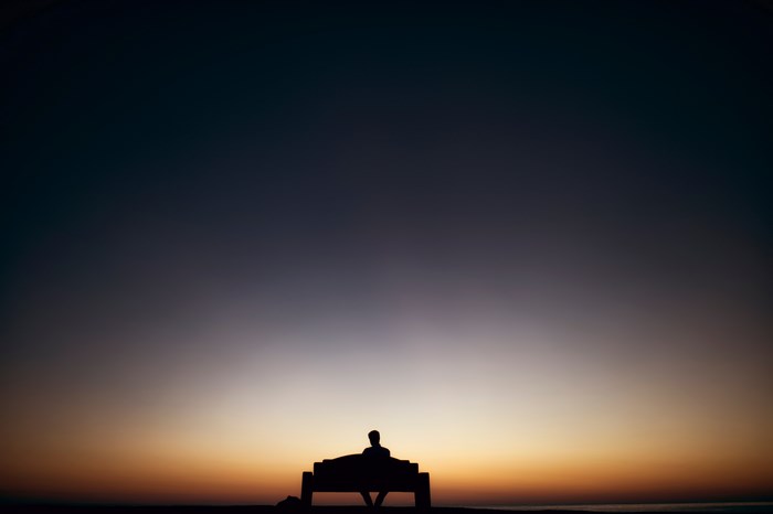 Man sitting on a bench at sunset
