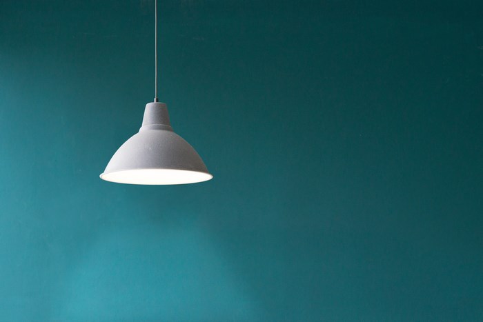 Minimalist grey pendant light against teal wall