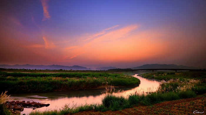 River flowing through a field at sunset