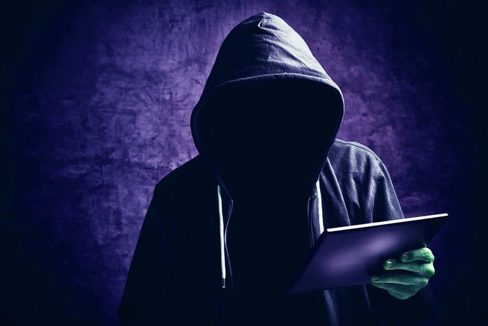 Anonymous Hacker in Dark Hoodie with Tablet