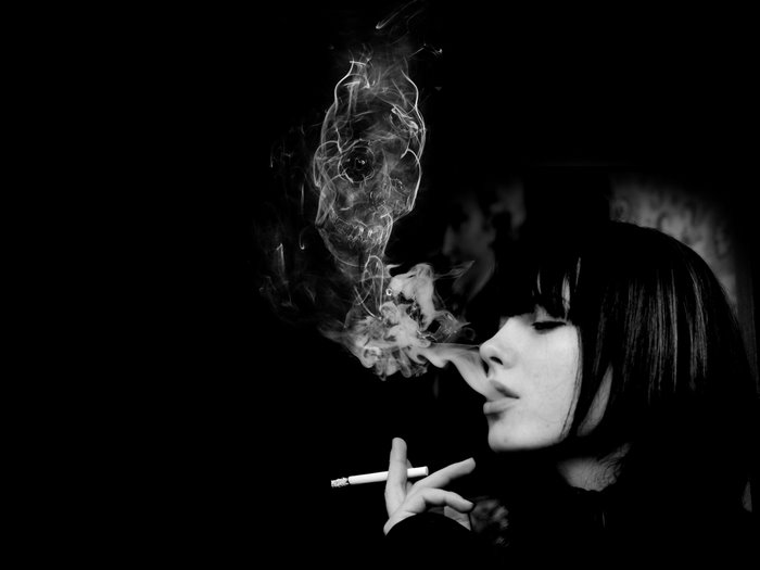 Woman smoking cigarette with skull smoke