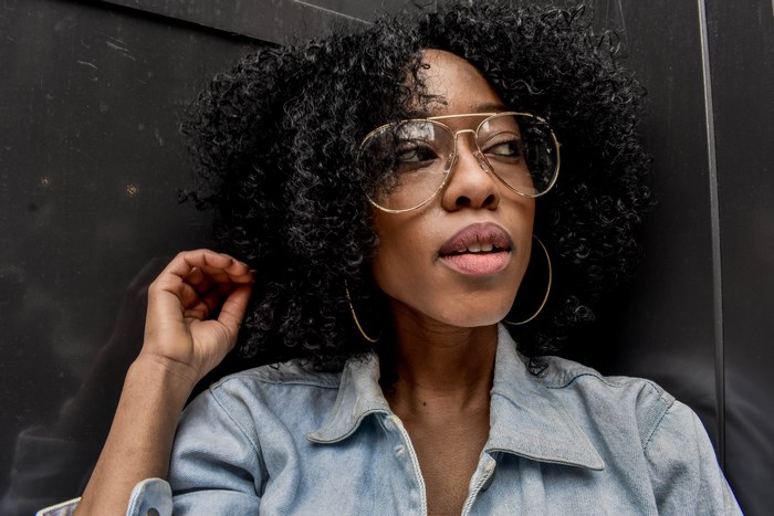 Woman with afro and glasses wearing denim jacket