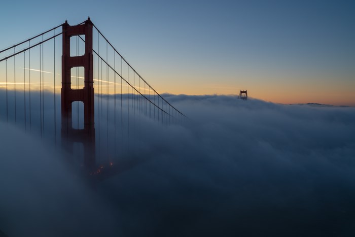 Golden Gate Bridge shrouded in fog at sunrise