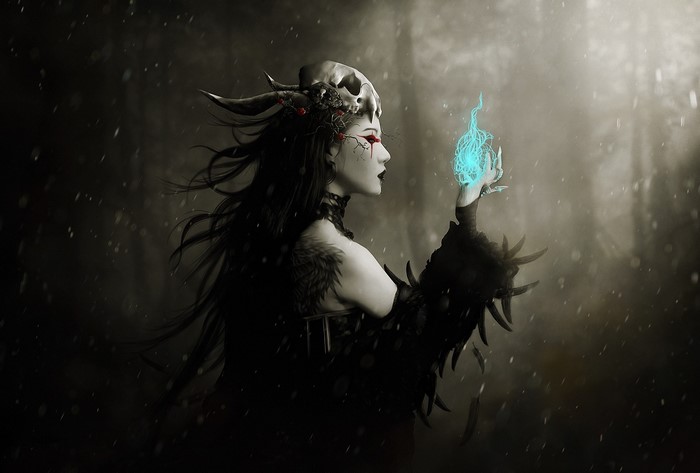 Witch with skull headdress conjures blue magic in snowy forest