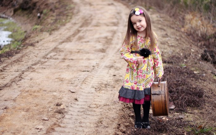 Girl with suitcase on a dirt road