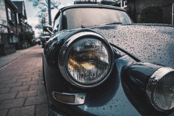 Close-up of a vintage car headlight on a rainy day