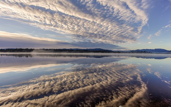 Sunrise over a misty lake with reflections