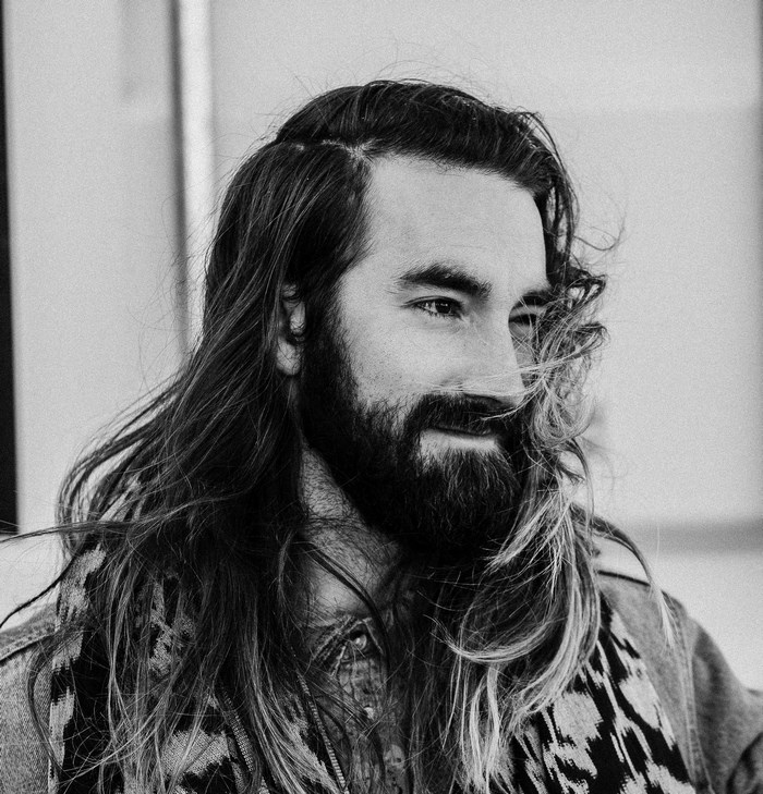 Man with long hair and beard in black and white