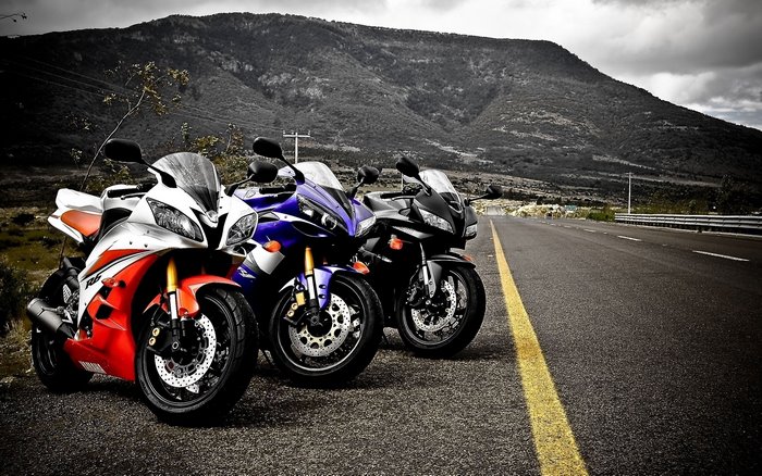 Three sport motorcycles parked on the side of a road