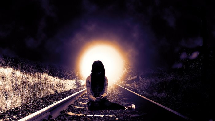 Lonely Girl Sitting on Railroad Tracks with Light