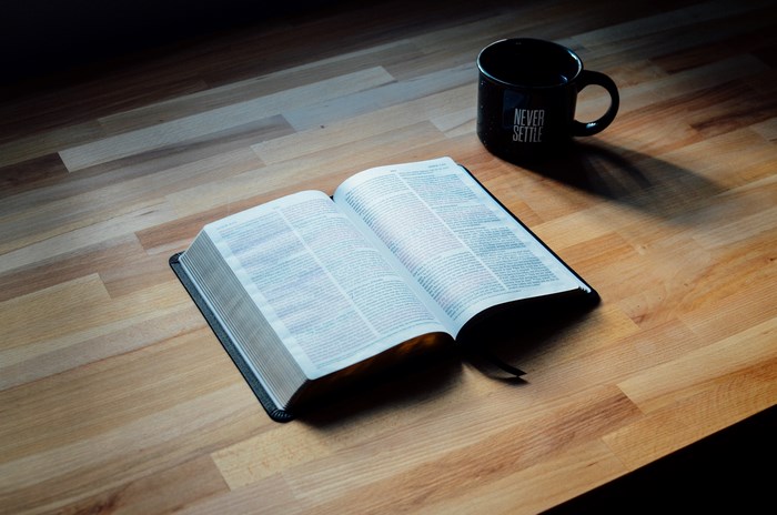 Open Bible and Coffee Mug on Wooden Desk