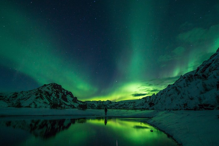 Person watches Aurora Borealis over a lake in Iceland