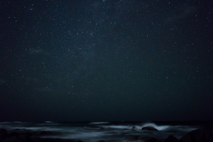 Night sky over the ocean with stars and waves