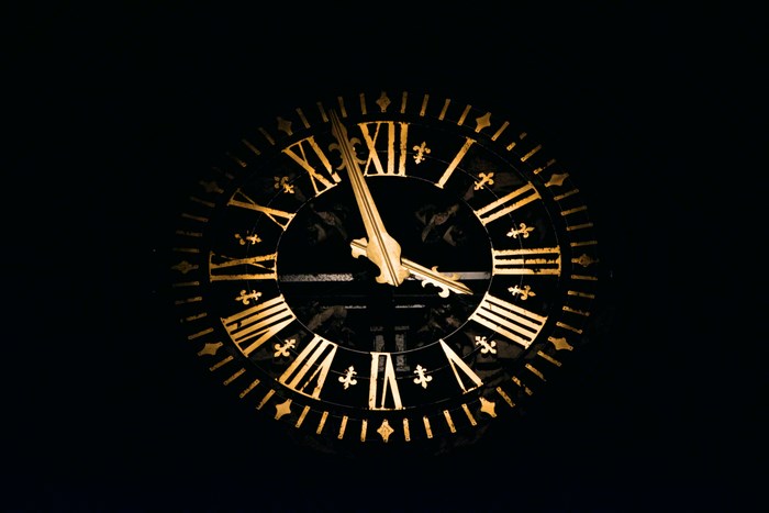 Close-up of a vintage gold Roman numeral clock face at night