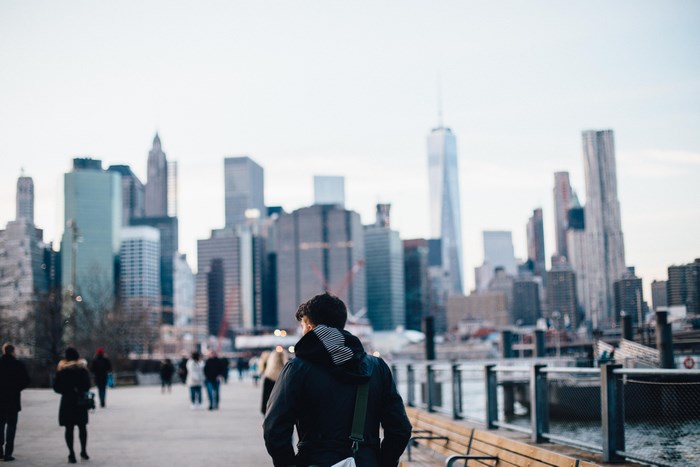 Man walking with New York City skyline in the background