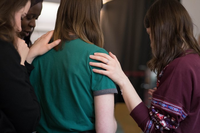 Women praying together with hands on shoulders