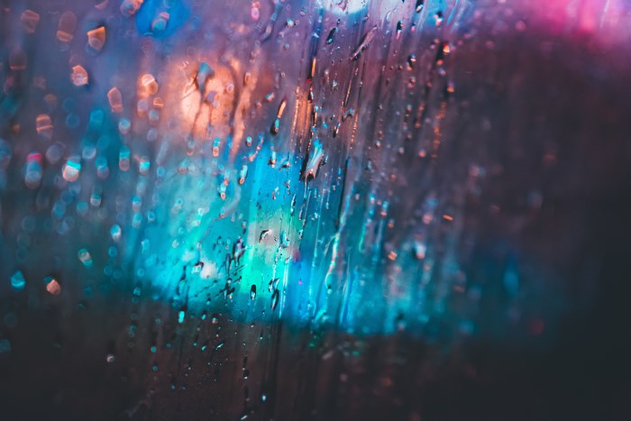 Raindrops on a window with blurred neon lights