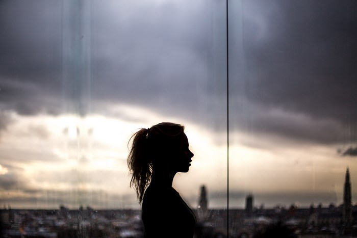 Silhouette of a woman against a stormy cityscape