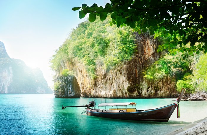 Longtail boat on turquoise water near limestone cliffs in Thailand