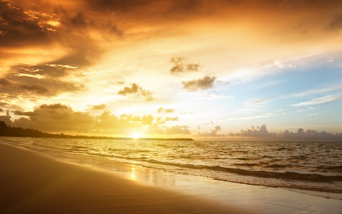 Sunset over a tropical beach with ocean waves