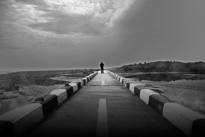 Solitary Figure on Isolated Road under Overcast Sky