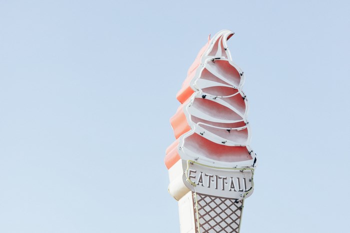 Neon ice cream cone sign that says "Eat It All"