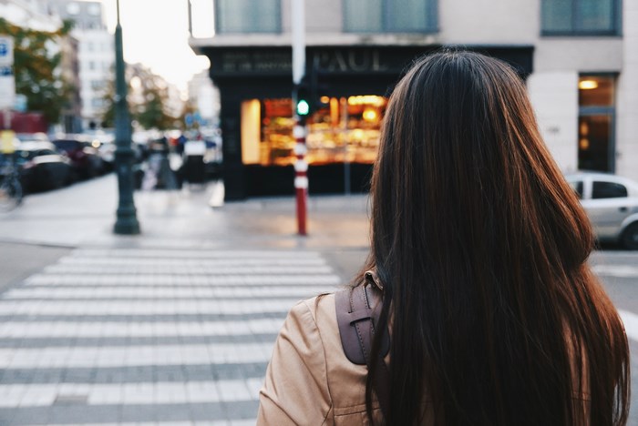 Woman crossing street in front of Paul store