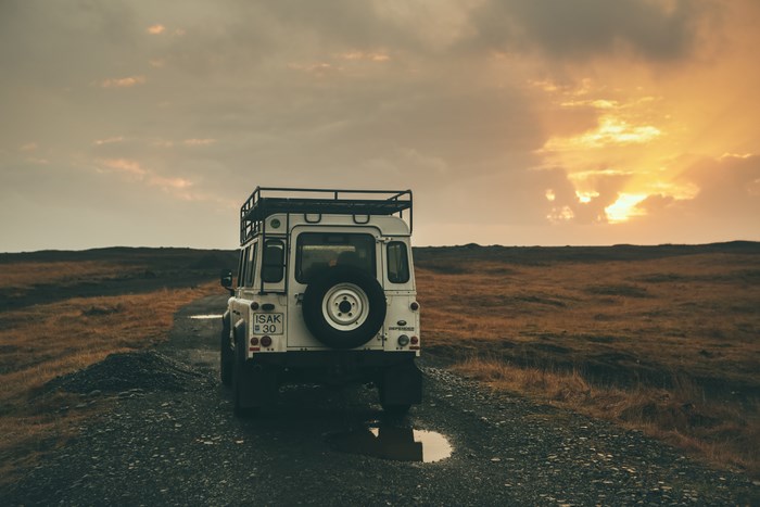 White Land Rover Defender on a dirt road at sunset in Iceland